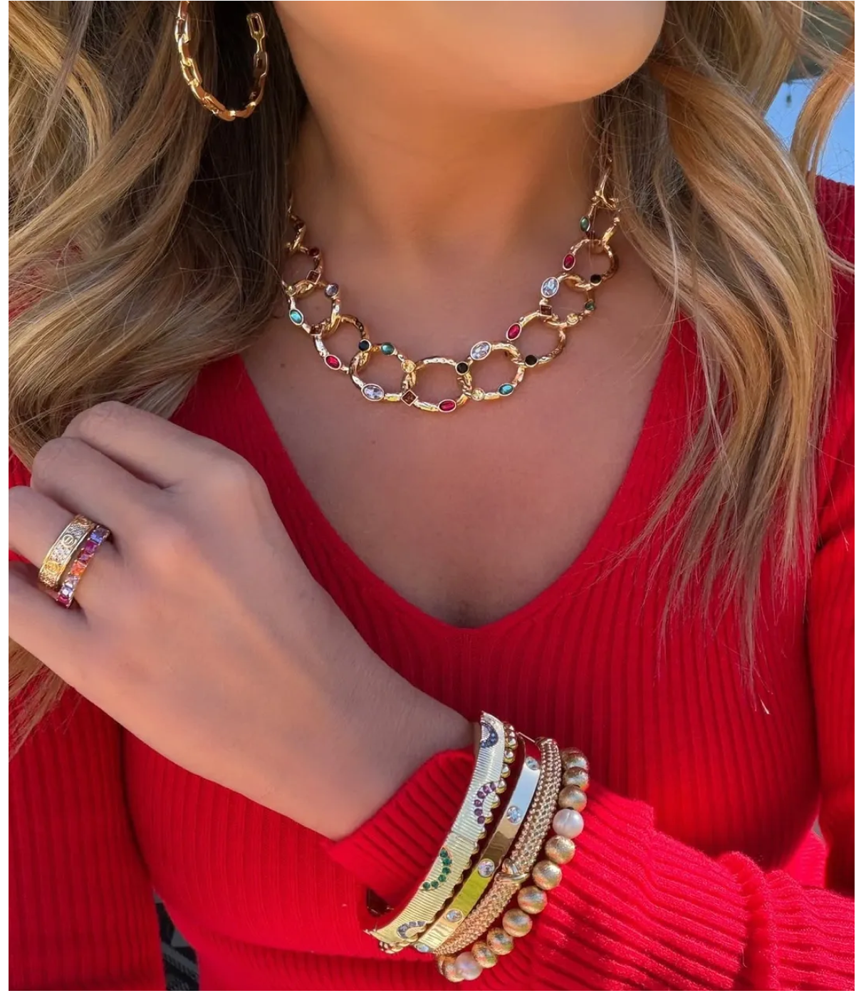 Woman wearing gold jewelry and red sweater